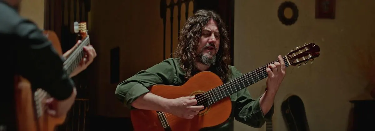 Guitarrista de verde cantando, con su compañero de espaldas