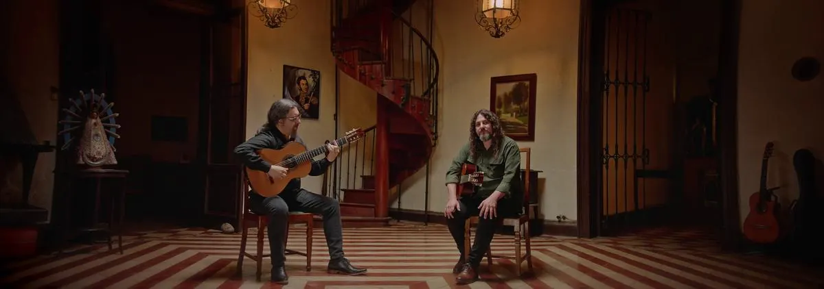 Los dos guitarristas sentados en el zaguán de la casa