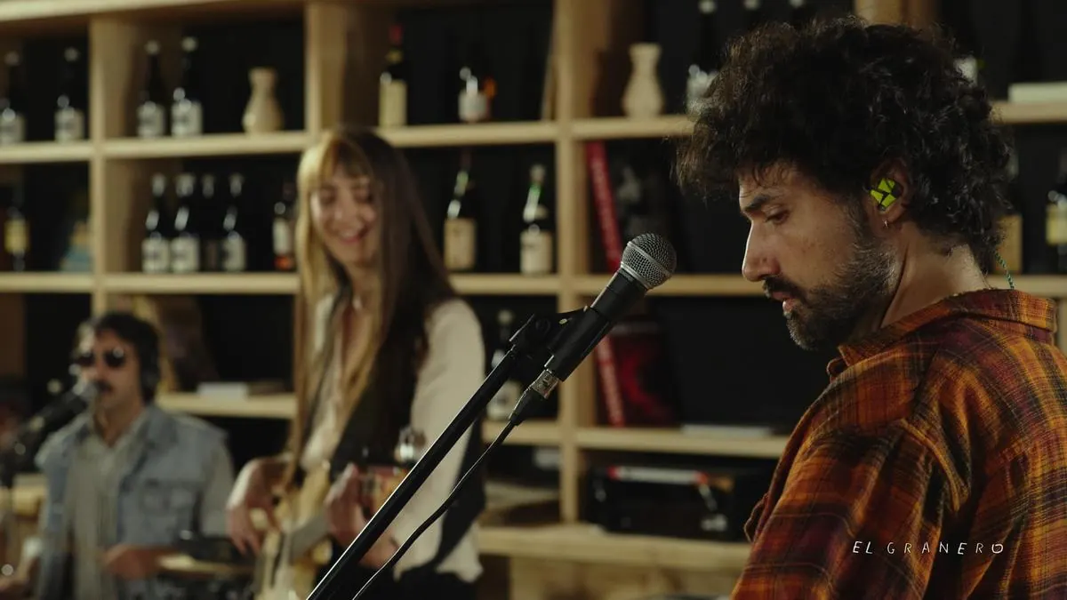 El cantante frente al micrófono, con la banda tocando detrás